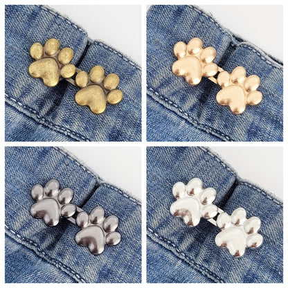 Four sets of dog paw waist tightener buttons, one each in bronze, golden, gunmetal and silver