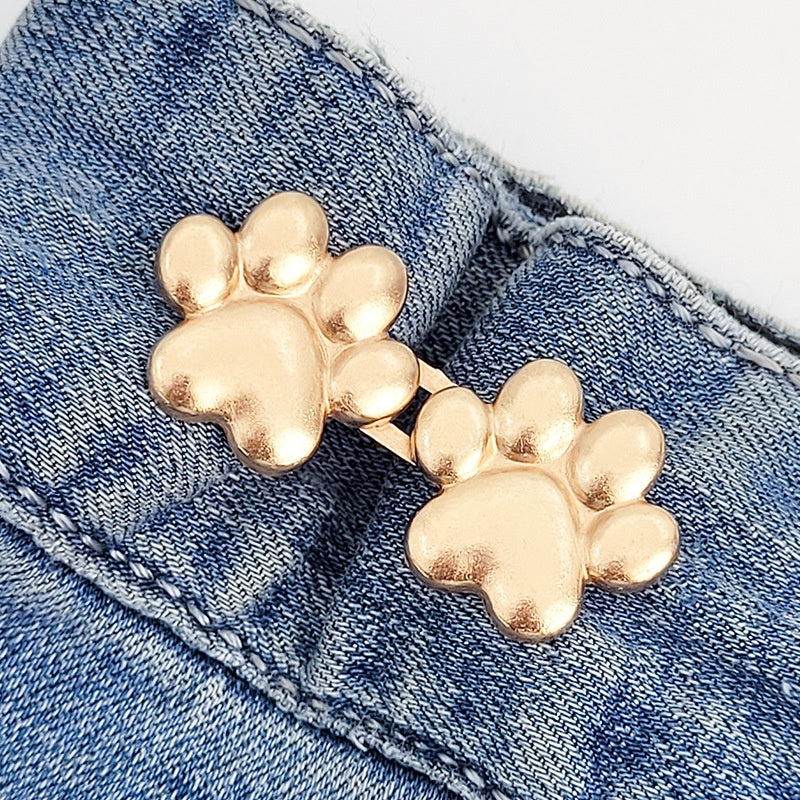One set of golden dog paw waist tightener buttons fastened on a denim jeans waistband