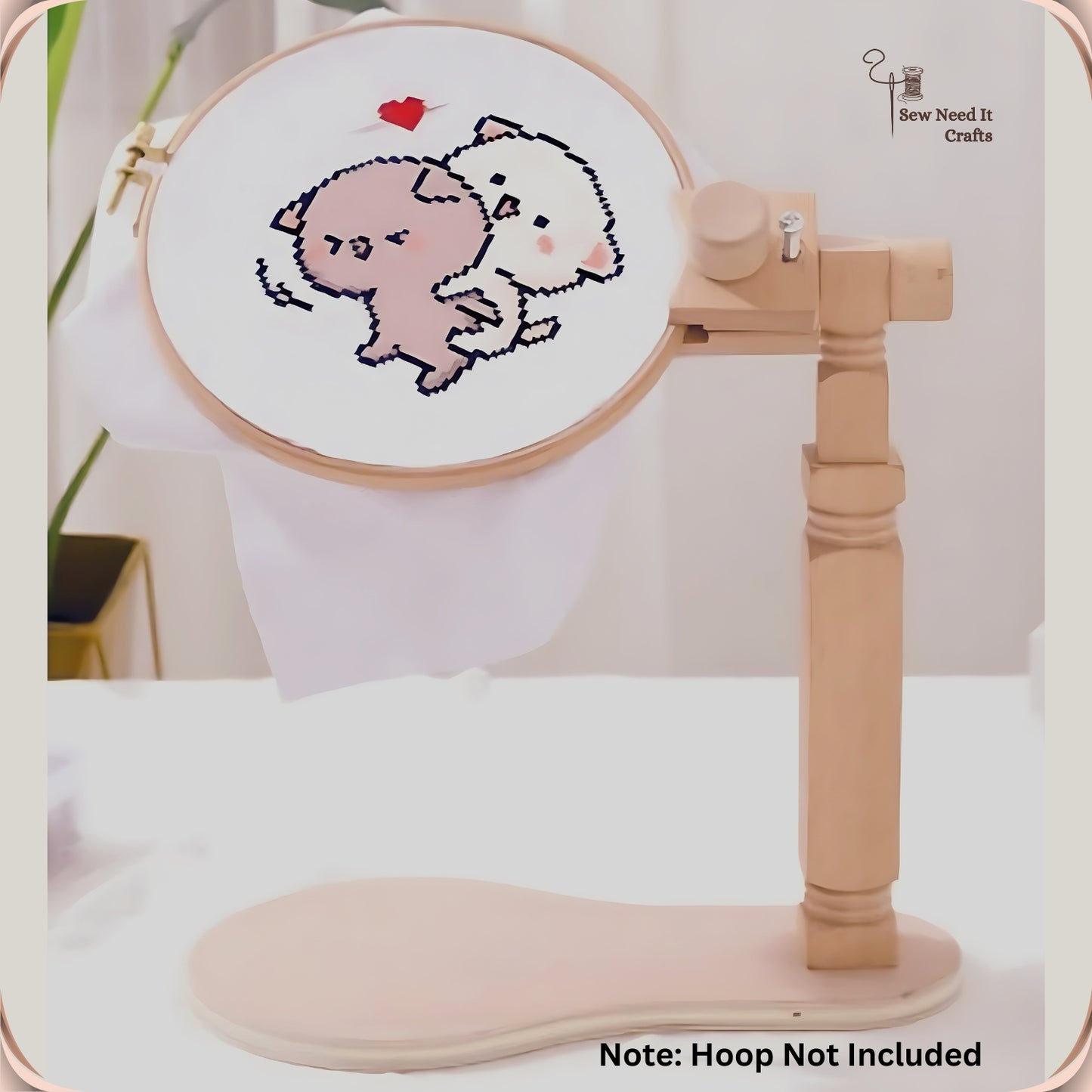 The stand holding a hoop with a cross-stitched bear design, base board resting on a table, hoop not included