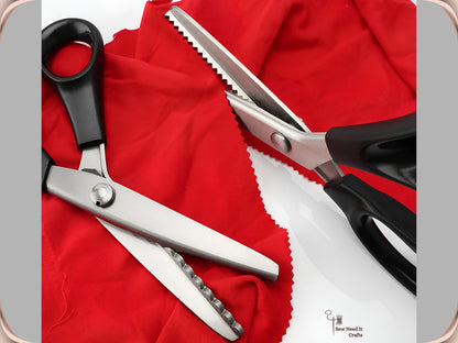 Two black-handled pinking shears resting on red fabric, one with a zigzag blade and one with a scalloped blade, beside a length of red fabric cut with a pinked edge