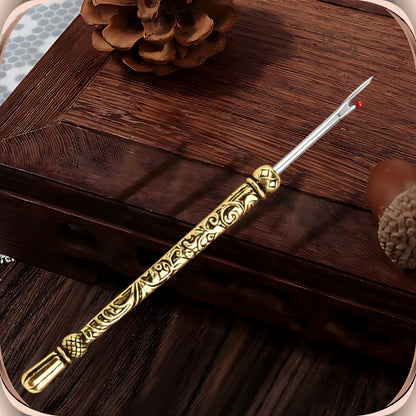 Antique Gold round handle seam ripper resting on a dark wooden box, showing the scroll engraved slim handle, faceted bead and smooth fluted end