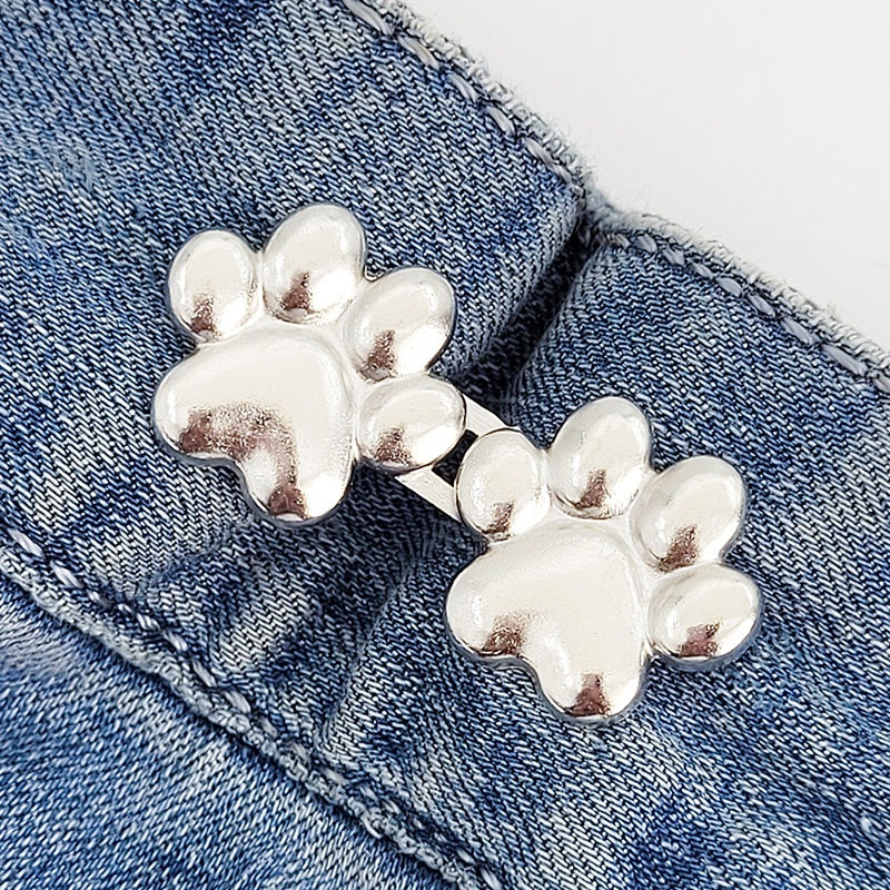 One set of silver dog paw waist tightener buttons fastened on a denim jeans waistband