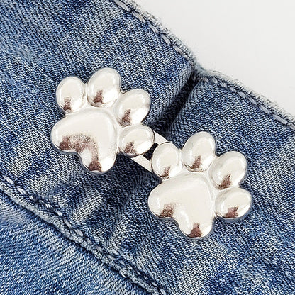 One set of silver dog paw waist tightener buttons fastened on a denim jeans waistband