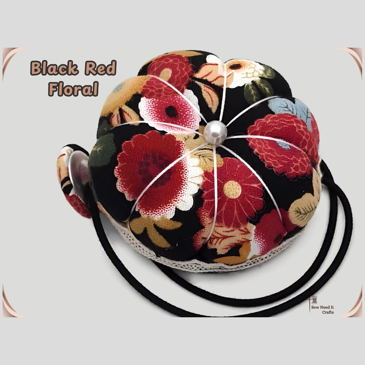 Black floral pumpkin wrist pin cushion with red and cream flowers, lace trim and black elastic wristband