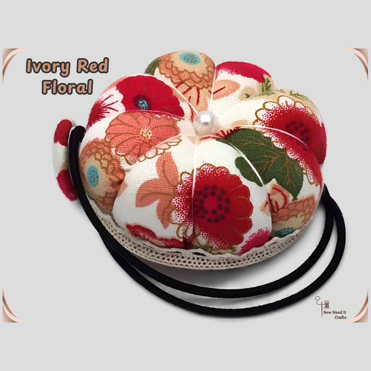 Ivory floral pumpkin wrist pin cushion with red, coral and green flowers, lace trim and black elastic wristband