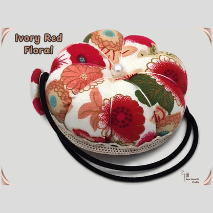 Ivory floral pumpkin wrist pin cushion with red, coral and green flowers, lace trim and black elastic wristband