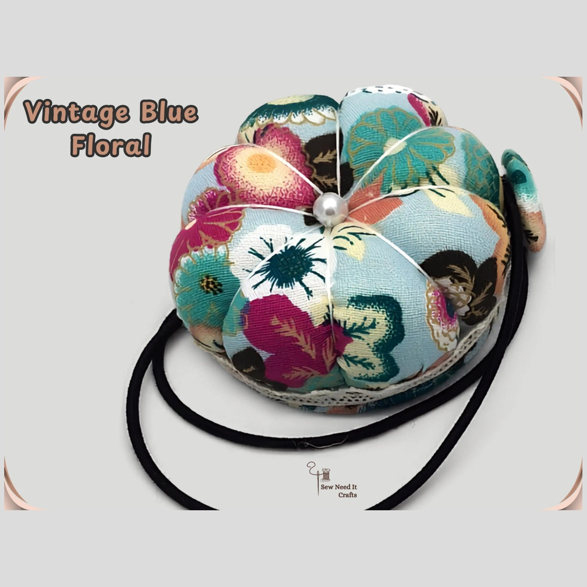 Vintage blue floral pumpkin wrist pin cushion with teal, pink and cream flowers, lace trim and black elastic wristband