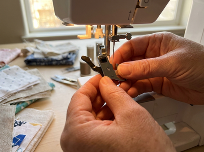 Hands attaching snap-on presser foot to Pfaff sewing machine