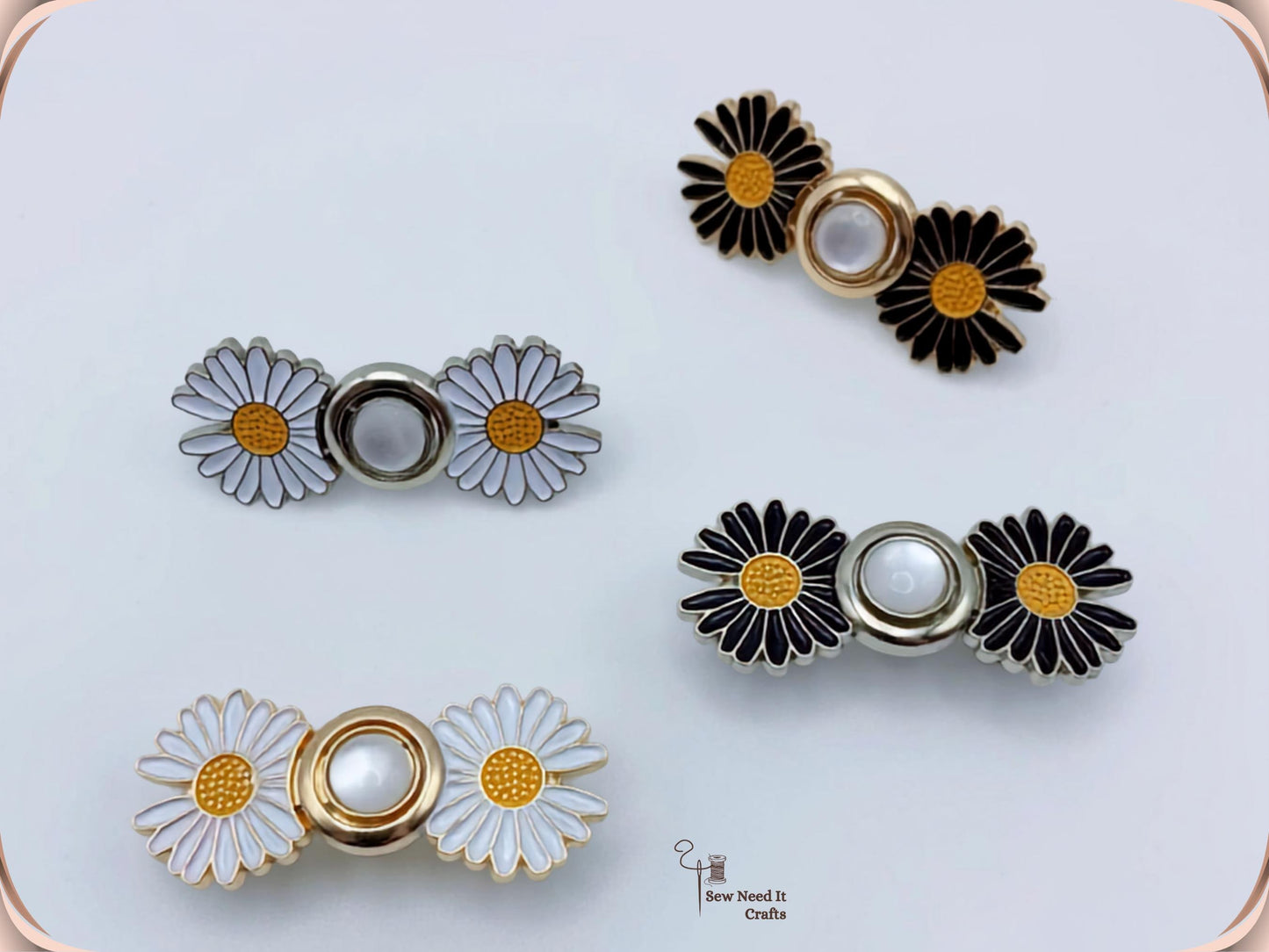 Four daisy waist adjusters in white and black enamel with gold and silver centres, photographed on a pale grey background