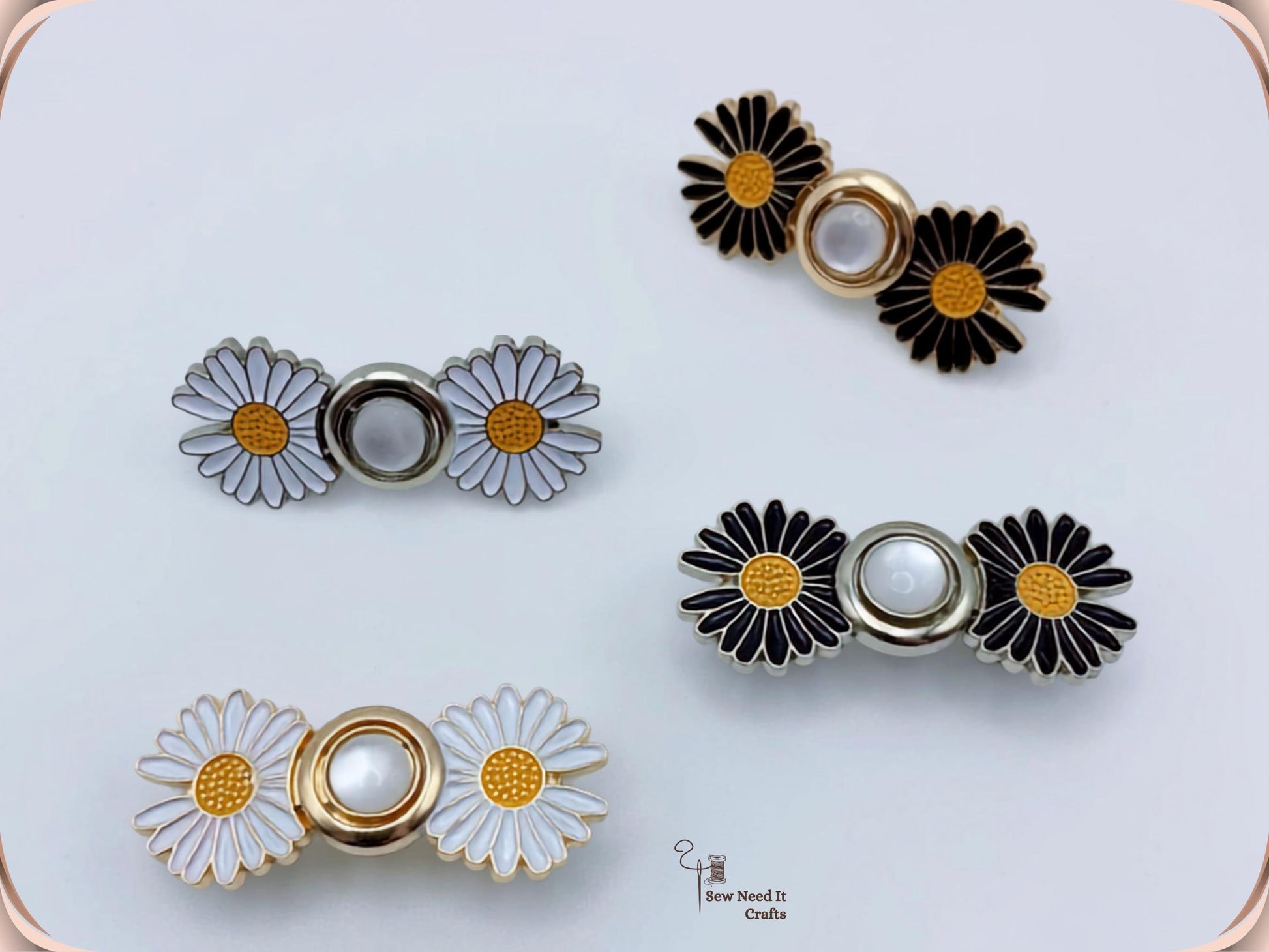 Four daisy waist adjusters in white and black enamel with gold and silver centres, photographed on a pale grey background