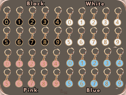All four colourways of the numbered stitch marker set - black, white, pink and blue - each showing markers numbered 0 to 9