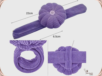 Dimensions diagram of the purple pumpkin wrist pin cushion showing a 22 cm band and a 6.5 cm cushion, with insets of the band coiled into a ring and a needle pushed into the cushion