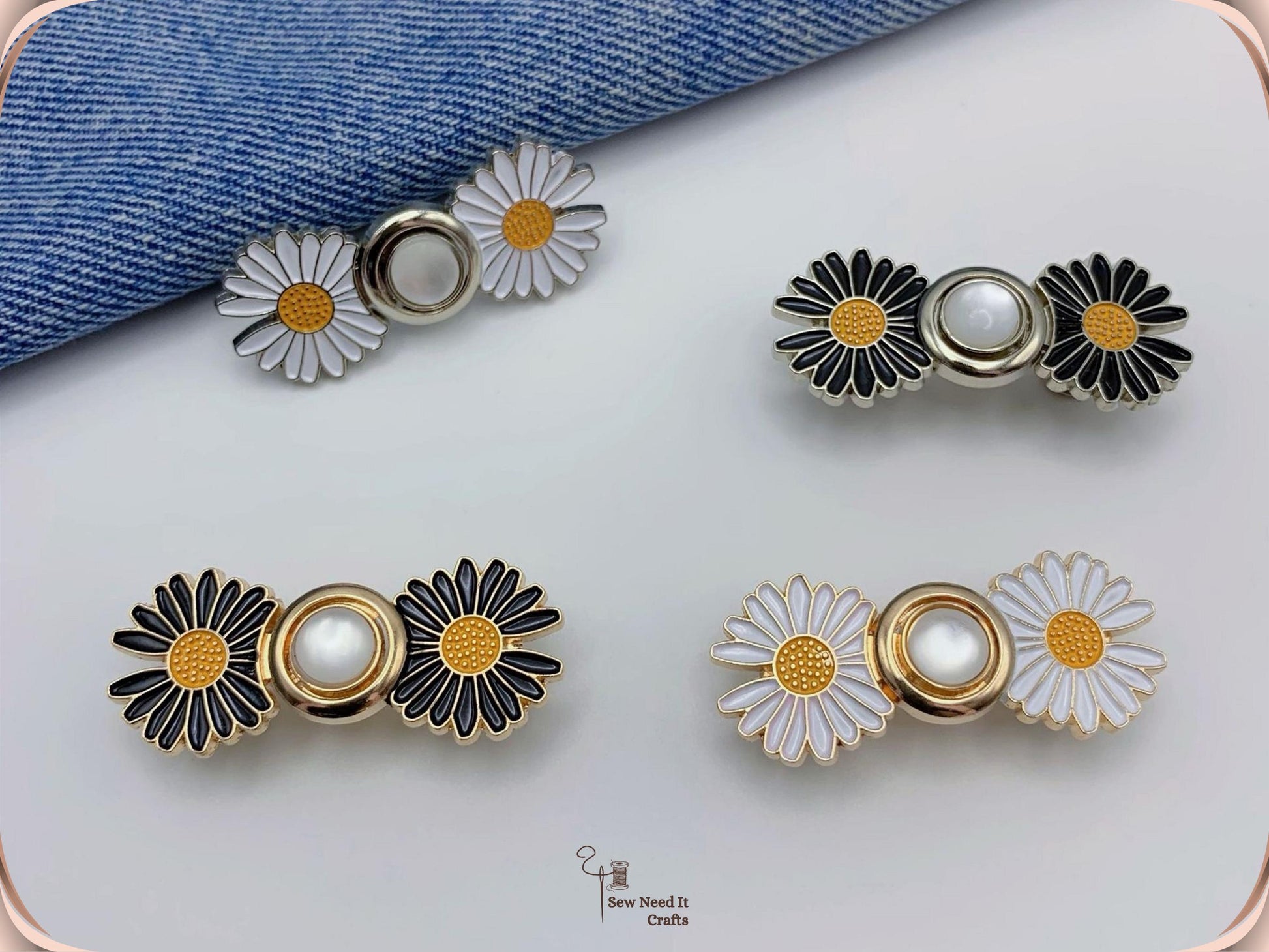 Four assembled daisy waist adjusters in black and white enamel with gold and silver finishes, arranged on white beside folded denim