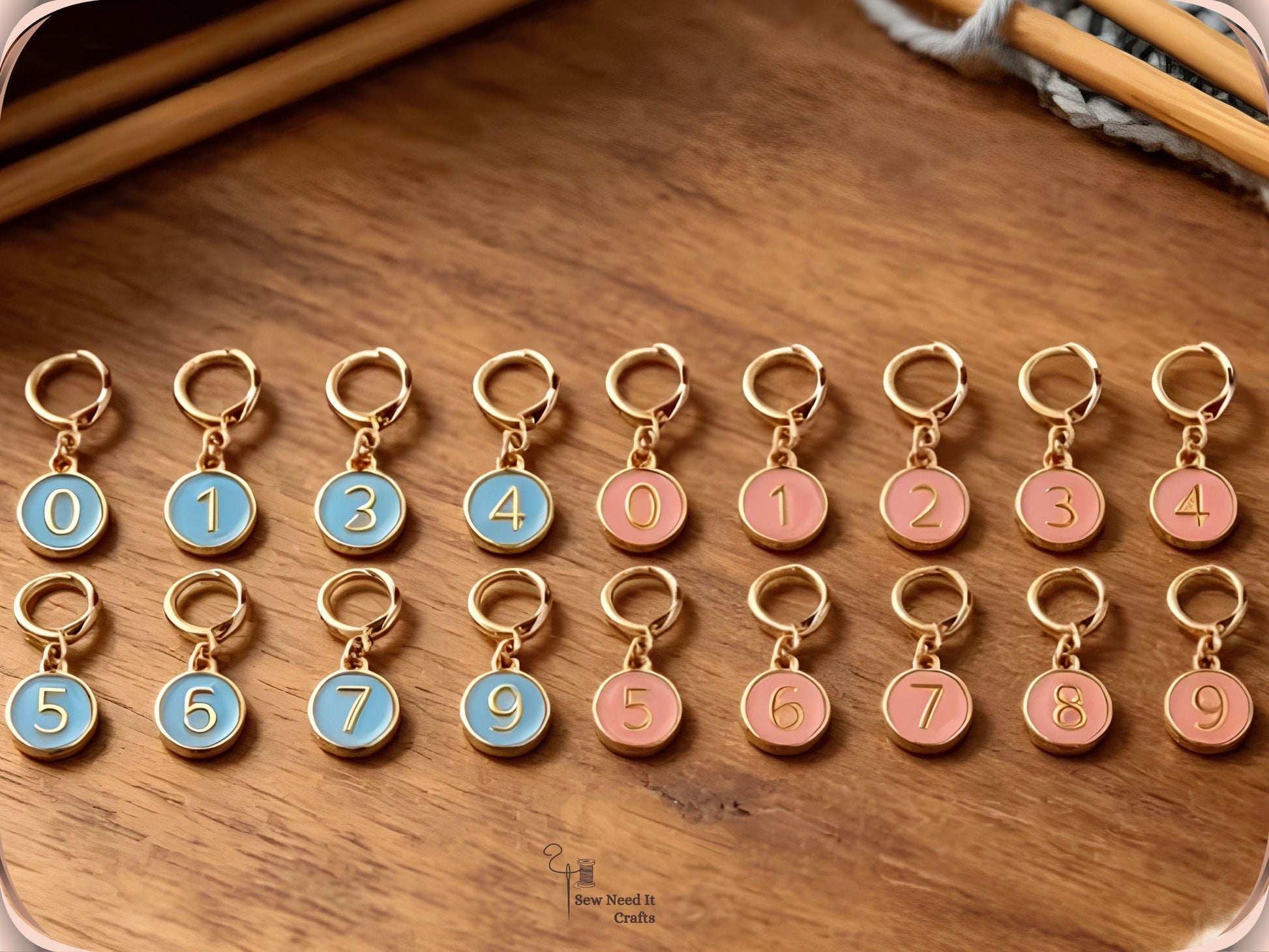 Blue and pink numbered stitch markers arranged in rows on a wooden surface with bamboo knitting needles and grey yarn