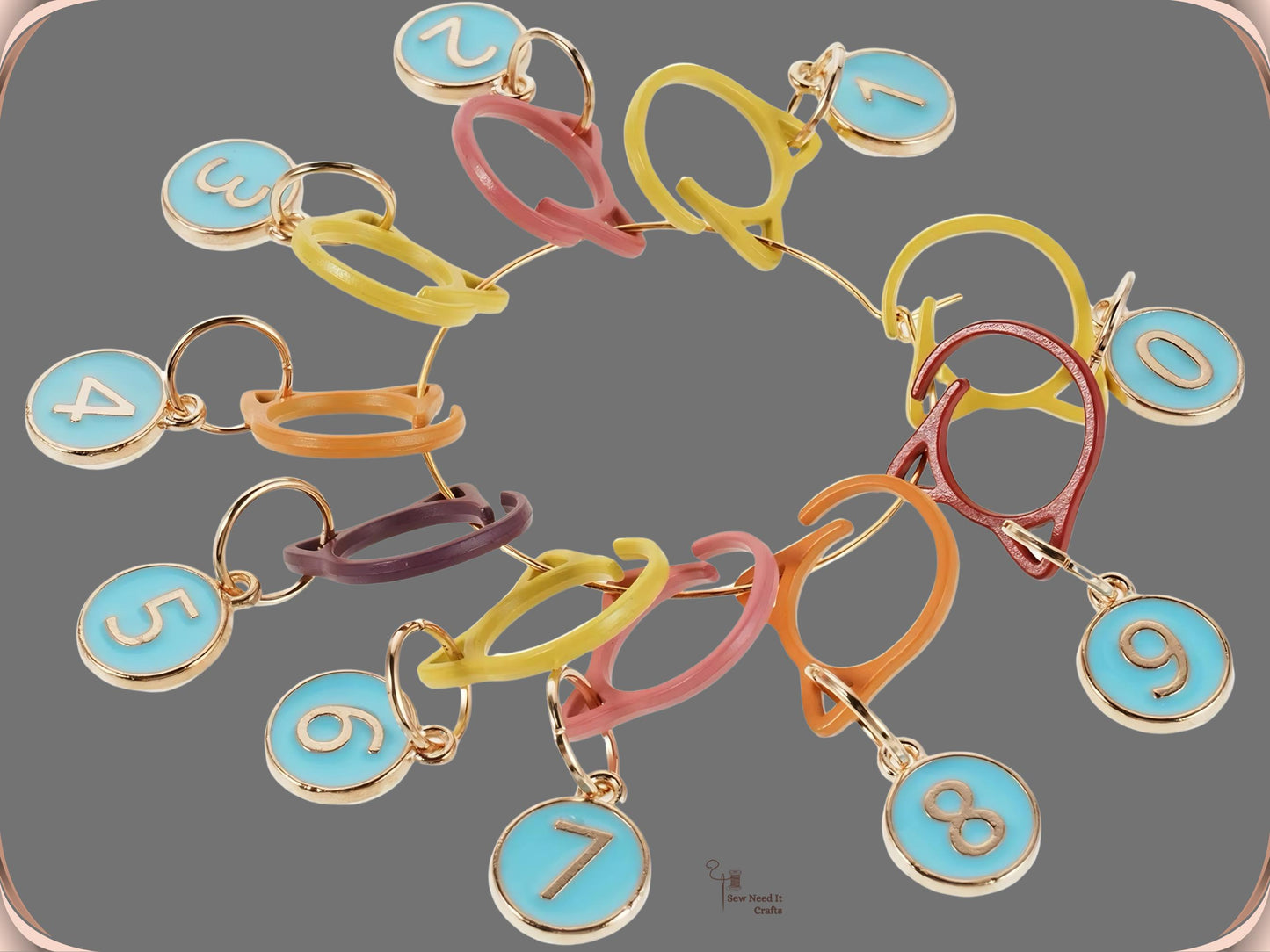 The Blue numbered stitch marker set arranged in a circle on a grey background, showing ten blue enamel charms numbered 0 to 9 on assorted-colour cat-ear clips