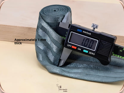 Digital caliper measuring a sage green striped elastic band at approximately 1 mm thick
