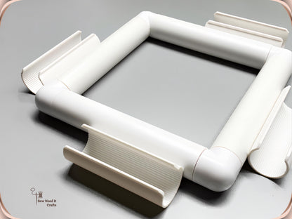 Assembled white square snap frame with its four ribbed clamps beside it