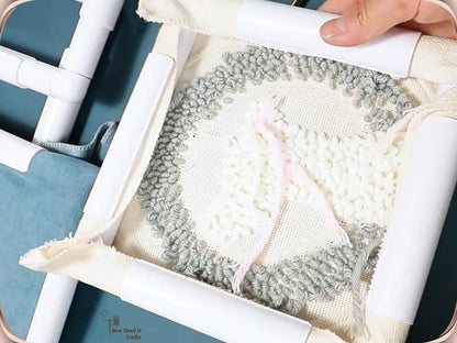 Close-up of looped grey and white punch needle work held tight in a white snap frame