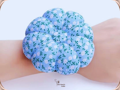 Sky blue floral pumpkin pin cushion worn on top of a wrist