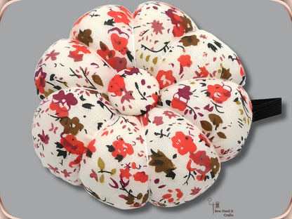 Cream pumpkin wrist pin cushion with red and brown flowers and black elastic band