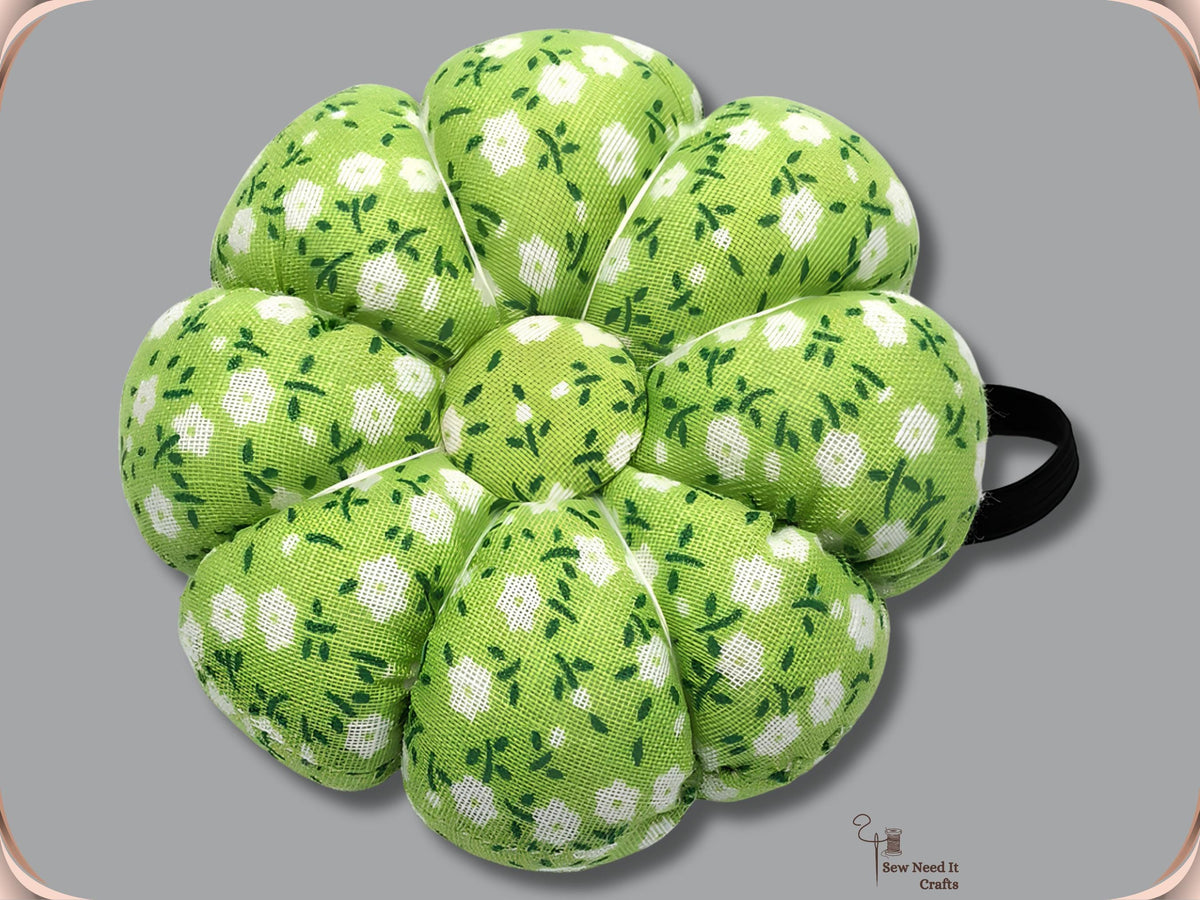 Lime green pumpkin wrist pin cushion with white flowers and black elastic band