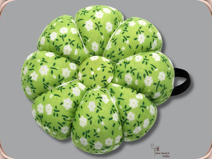 Lime green pumpkin wrist pin cushion with white flowers and black elastic band