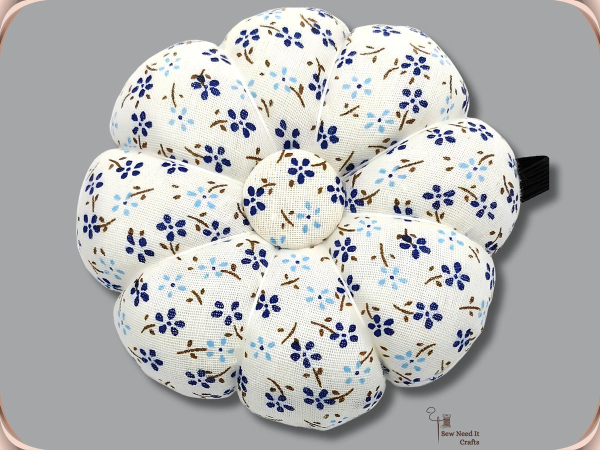 White pumpkin wrist pin cushion with navy and light blue flowers and black elastic band