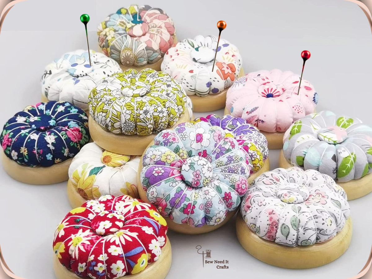 Assorted floral wooden-base pumpkin pin cushions with pins standing in the tops