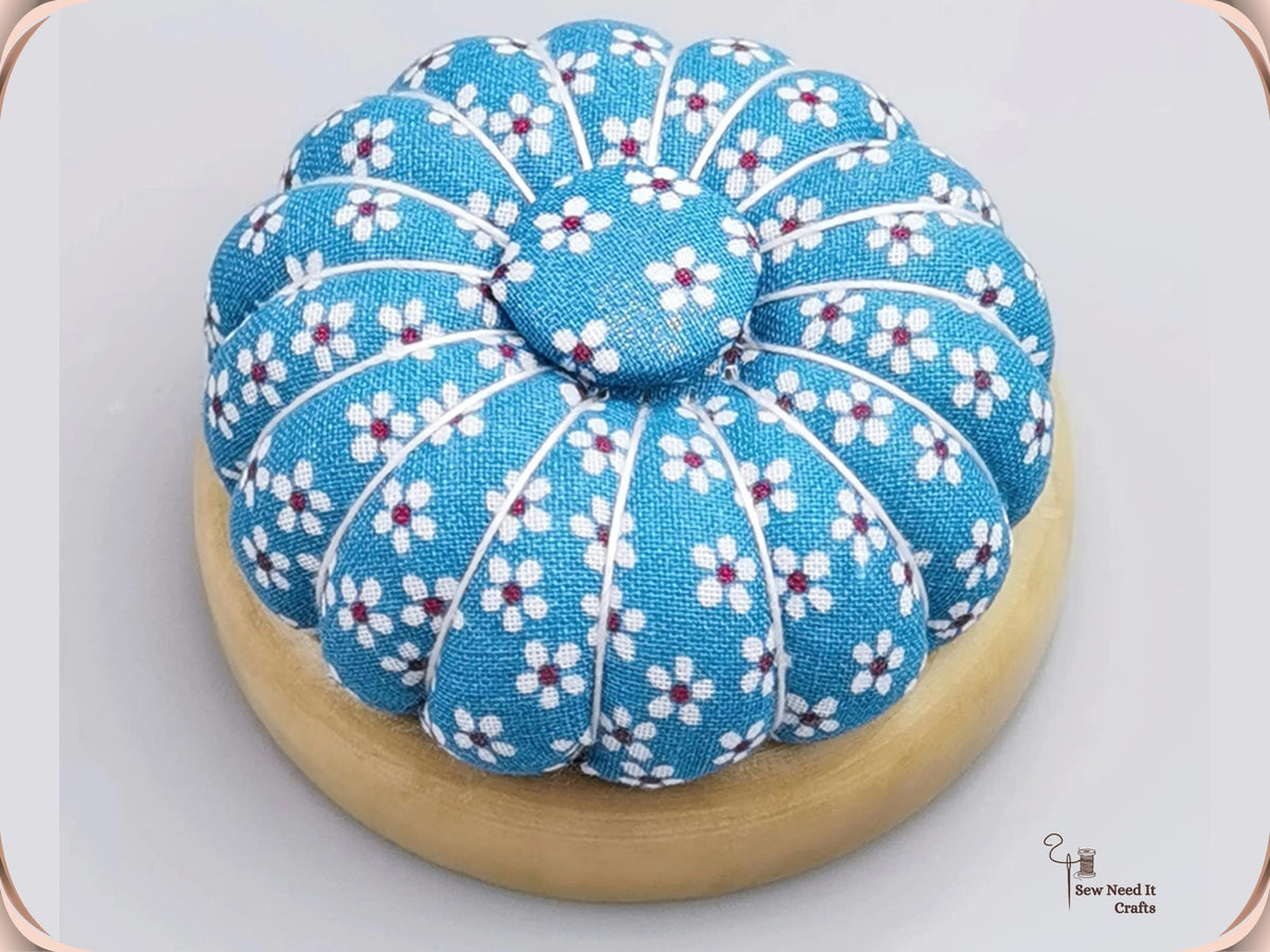 Blue Floral pumpkin pin cushion with white flowers on a natural wooden base