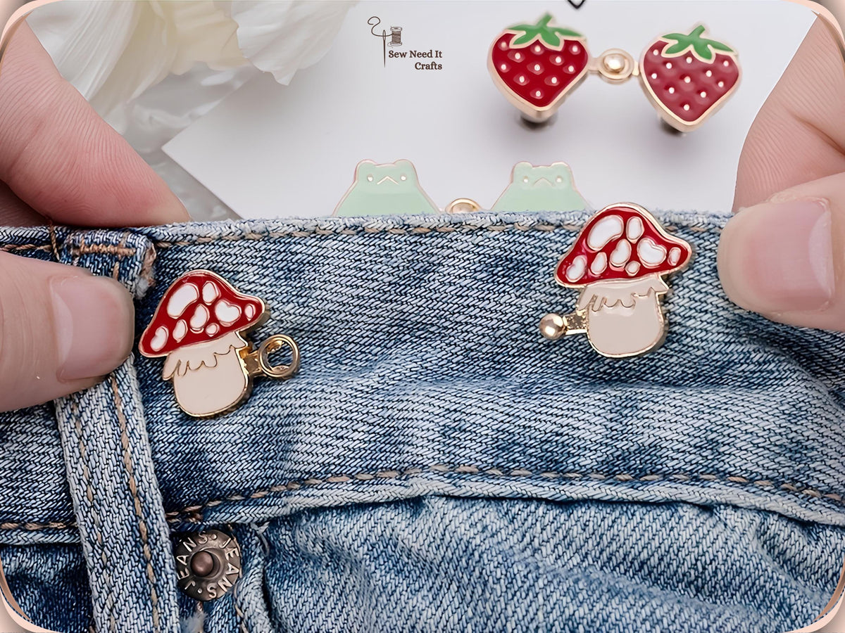 Hand fitting red mushroom waist pins to a jeans waistband, with strawberry and frog pairs behind