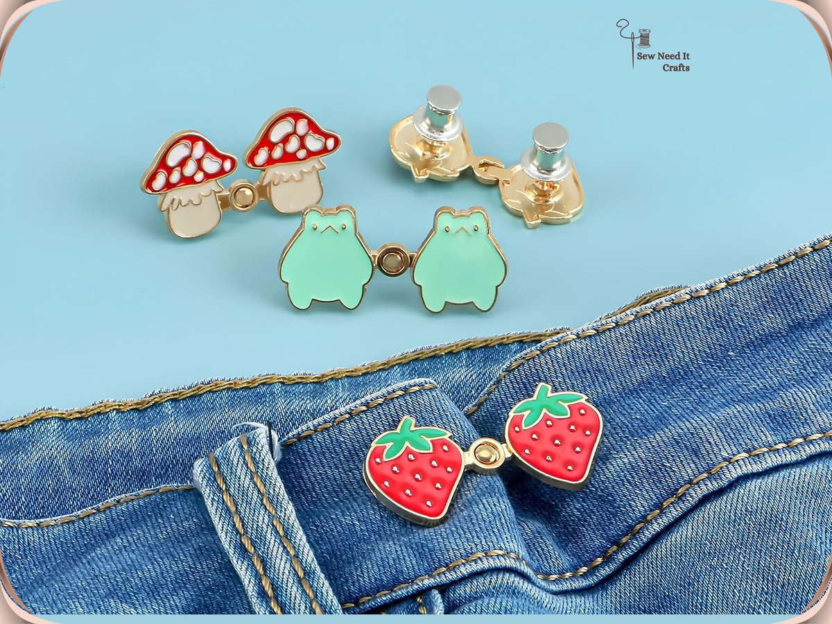 Mushroom and frog waist pins with silver back caps above a strawberry pair snapped onto a jeans waistband