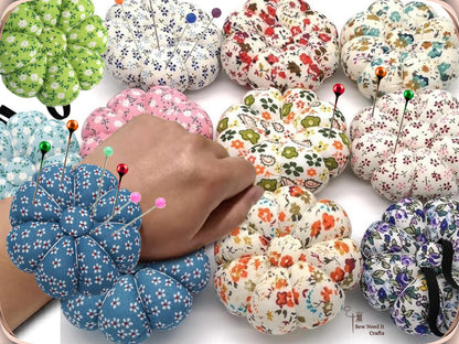 Denim Blue wrist pin cushion full of pins worn on a wrist, surrounded by other floral print pin cushions