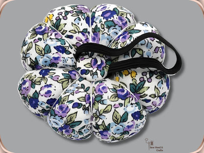 Purple Floral pumpkin wrist pin cushion turned to show the black elastic band on the underside