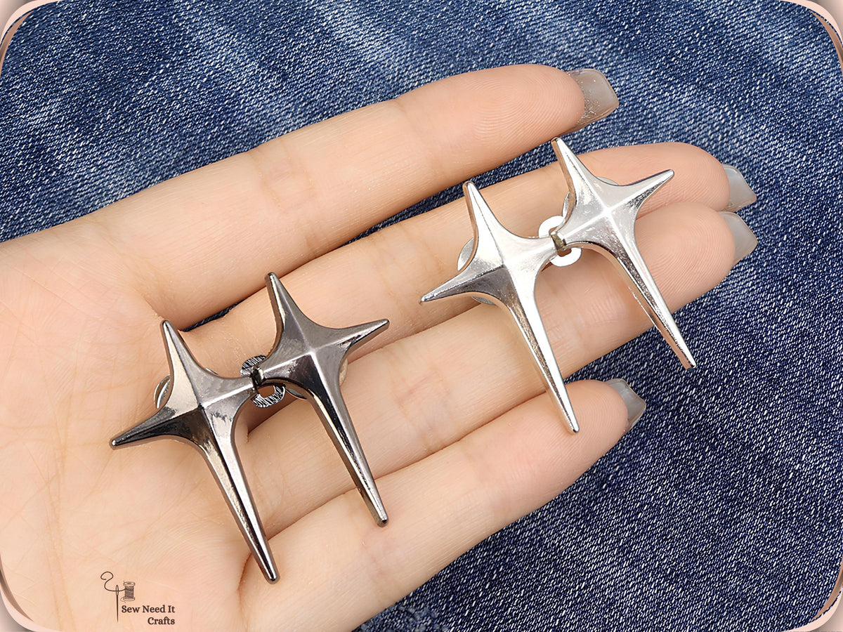 Hand holding gunmetal and silver sparkle star jean pins, each pair hooked together