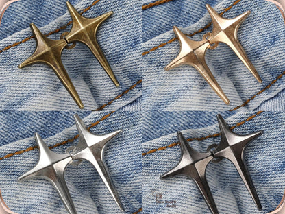 Bronze, golden, silver and gunmetal sparkle star jean pins, each pair hooked together on light denim
