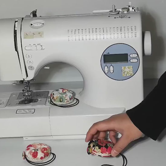Video: a floral wrist pin cushion looped around the arm of a sewing machine, then taken off and worn on the wrist