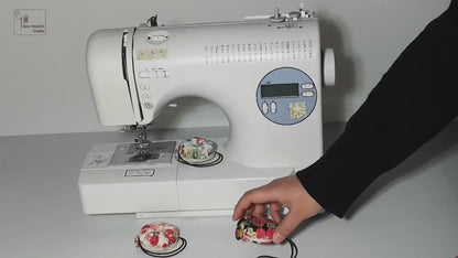 Video: a floral wrist pin cushion looped around the arm of a sewing machine, then taken off and worn on the wrist