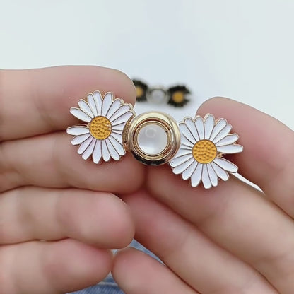 Video showing a white and gold daisy waist adjuster taken apart into its two halves, each pinned through the waistband of blue jeans and locked with its pin back, then buckled together to draw the waist in
