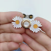 Video showing a white and gold daisy waist adjuster taken apart into its two halves, each pinned through the waistband of blue jeans and locked with its pin back, then buckled together to draw the waist in