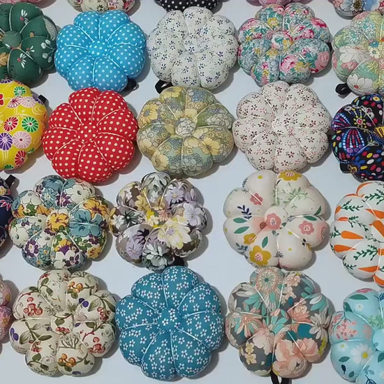 Video: overhead view panning across a large assortment of fabric pumpkin wrist pin cushions in many prints