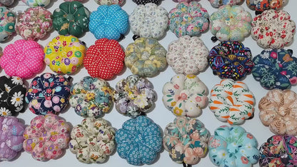 Video: overhead view panning across a large assortment of fabric pumpkin wrist pin cushions in many prints