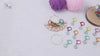 Video demonstration of the numbered cat-ear stitch markers: the full set shown on its gold-tone storage ring, then markers clipped onto a cream knitted swatch on the needles, and finally clipped into crochet worked with a hook