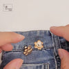 Fitting a paw waist adjuster to jeans: unlocking the pin cover, pushing the pin through the denim waistband and locking the cover behind