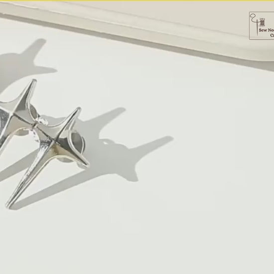 Video: gold, silver and gunmetal sparkle star jean pins, then a silver pair being pinned, capped and hooked together to take in a light-wash jeans waistband