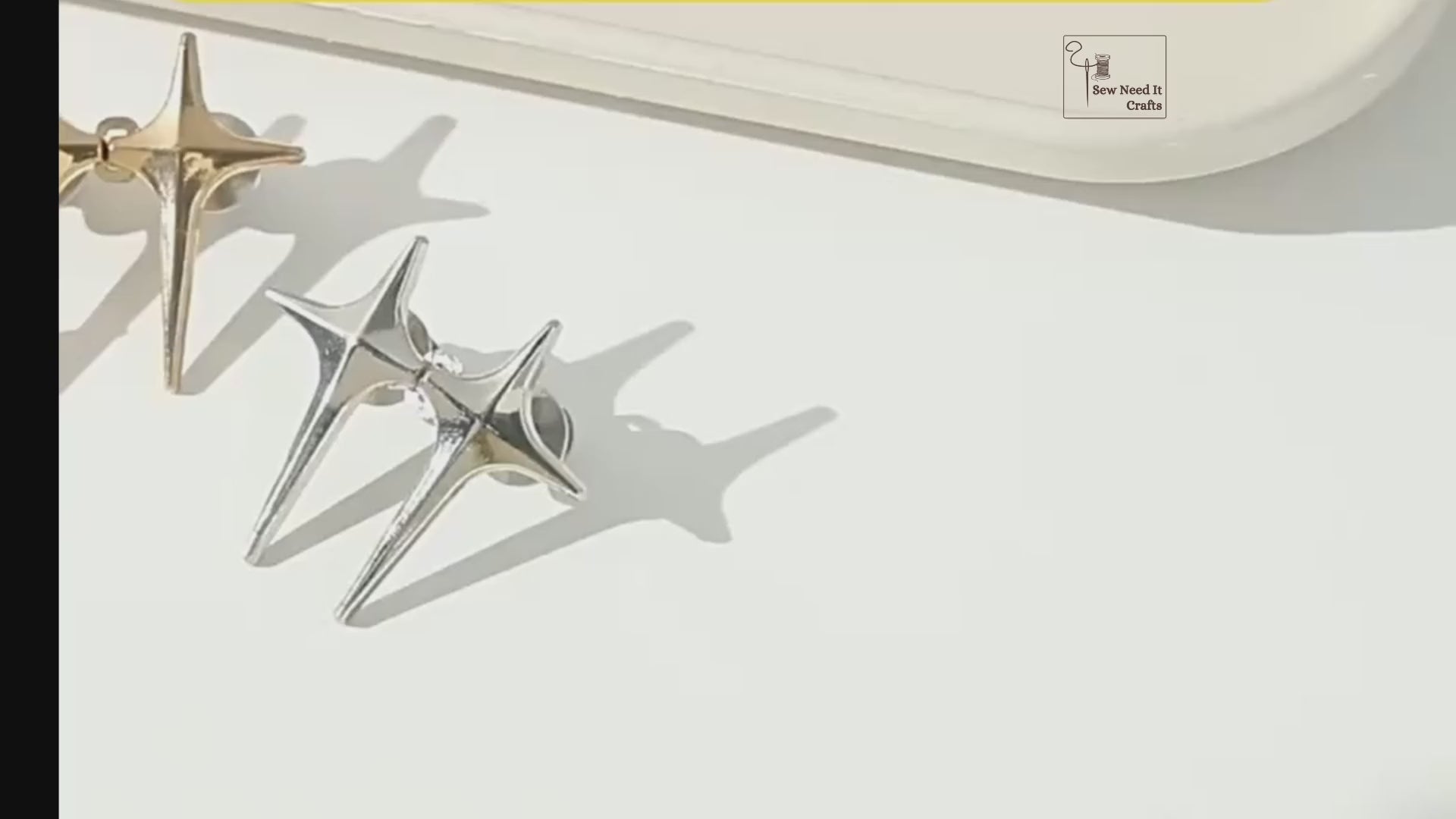 Video: gold, silver and gunmetal sparkle star jean pins, then a silver pair being pinned, capped and hooked together to take in a light-wash jeans waistband