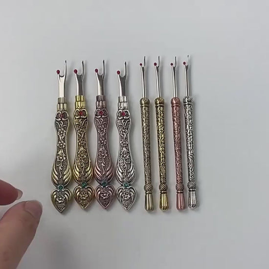 Video showing the full range of vintage style seam rippers in both flat and round handles, close-ups of the engraved metal and the stainless fork blade with its red safety ball, and the tool unpicking a machine-sewn seam in cotton fabric